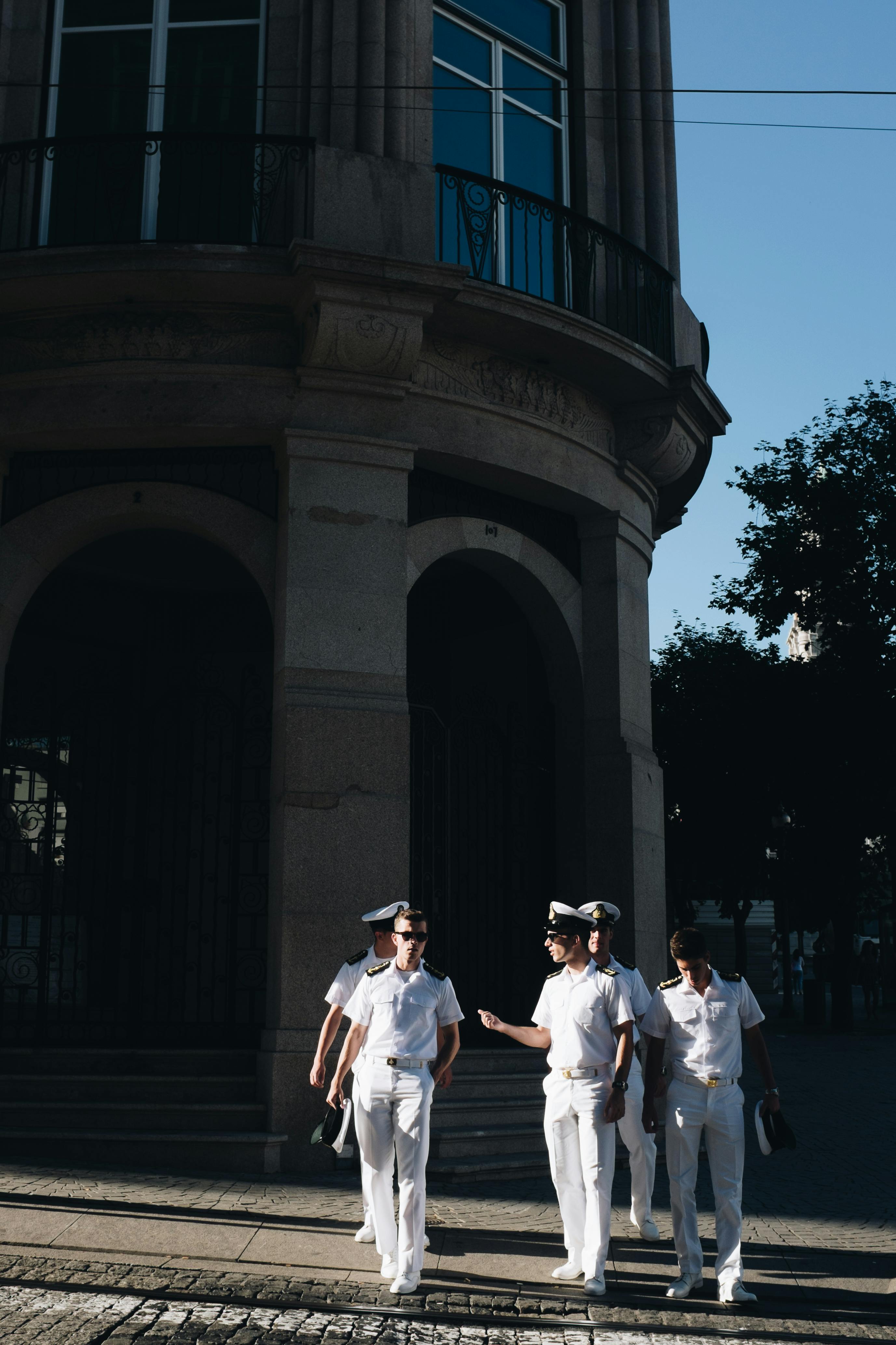 five navy officers standing near building
