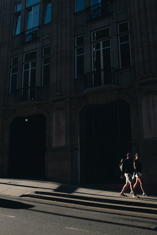 Two People Walking Near High Rise Building