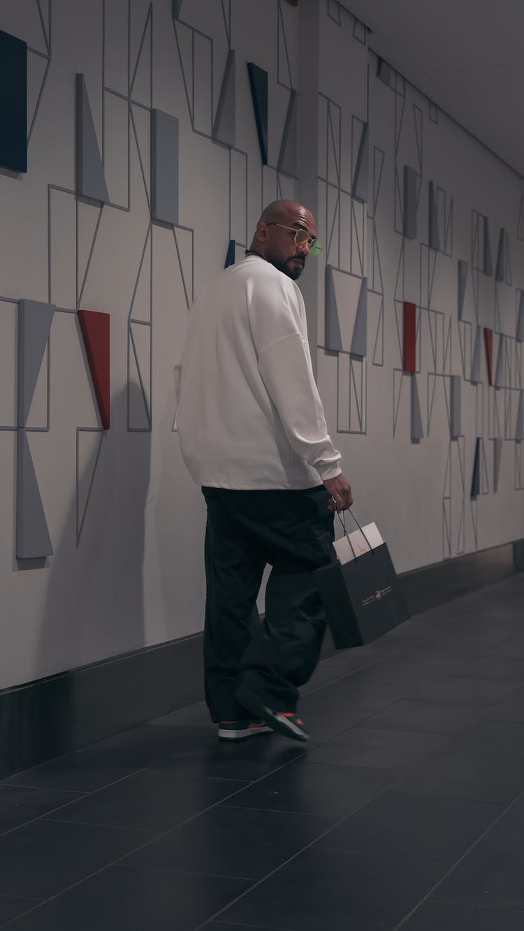 Fashionable Man With A Paper Bag Walking And Looking Over His Shoulder 