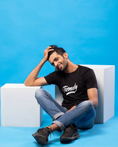 Young Man in a Casual Outfit Posing in Studio against Blue Background 