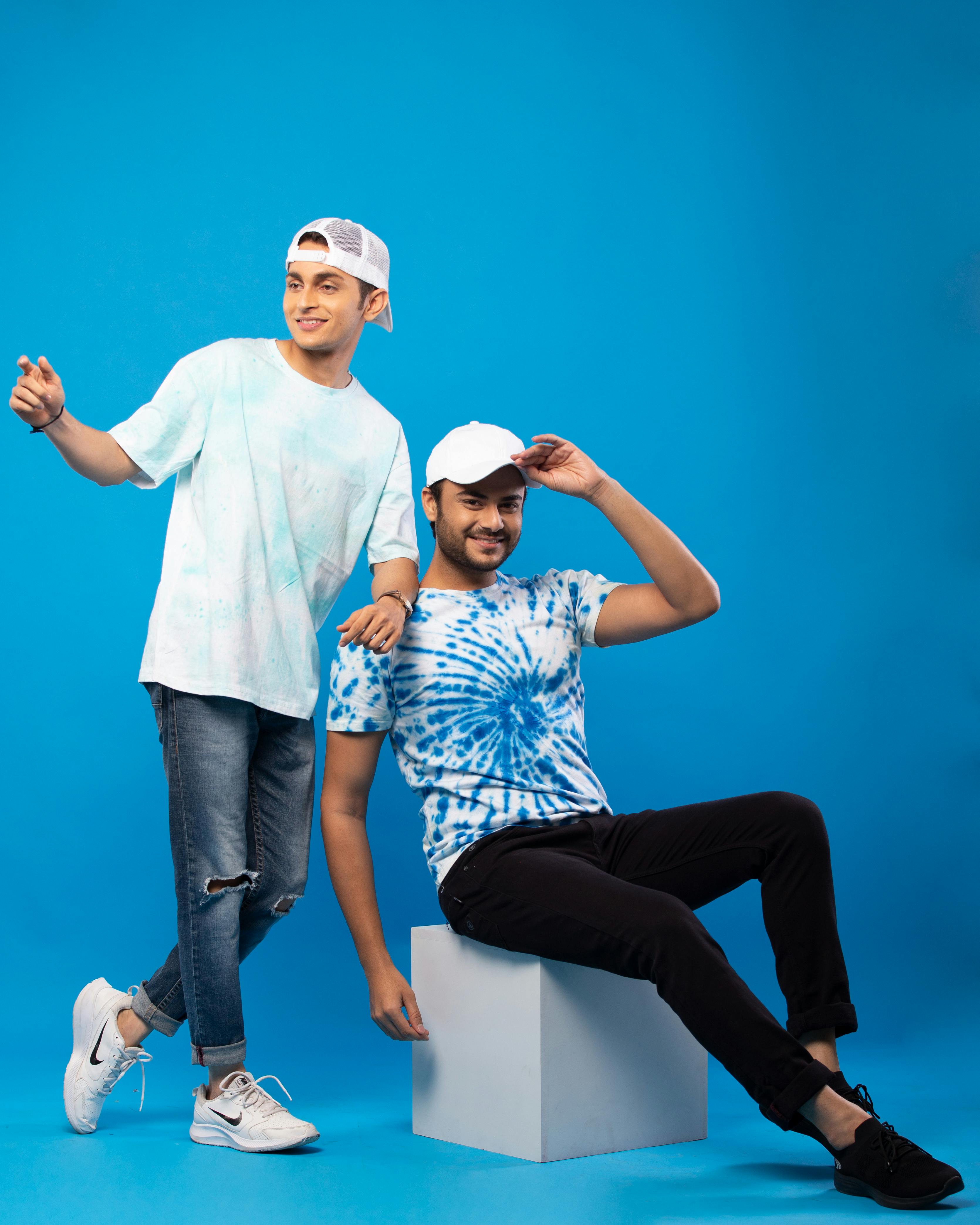 free photo of two men in casual outfits posing in studio against blue background