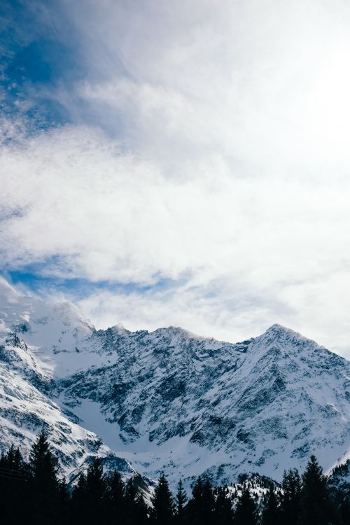 Free Scenic winter view of snow-covered mountains beneath a cloudy sky. Stock Photo