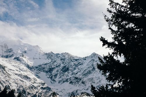 Free A serene winter landscape showcasing snow-covered mountains beneath a partly cloudy sky. Stock Photo