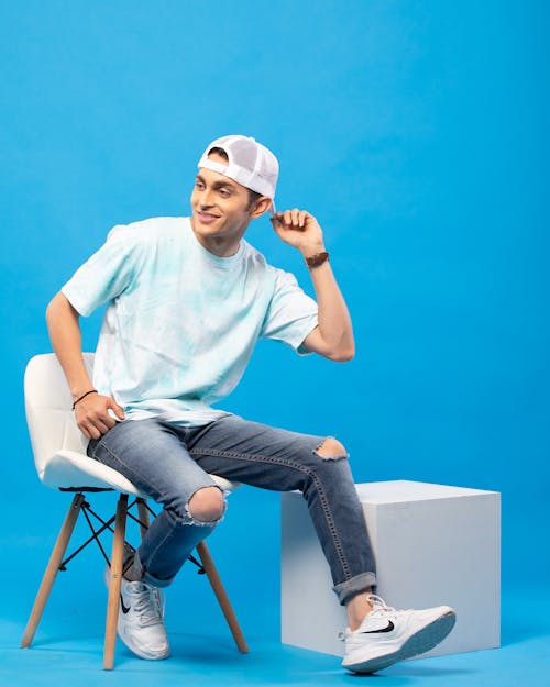 Young Man in a Casual Outfit Posing in Studio against Blue Background 
