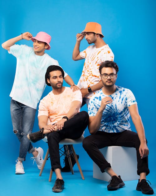 Group of Young Men in Casual Outfits Posing against Blue Background 