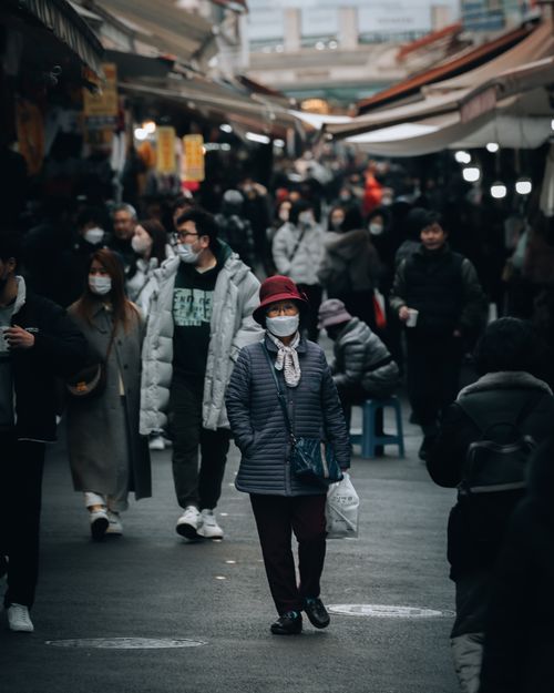Free Busy urban market filled with masked people shopping in cold weather. Perfect for depicting urban life. Stock Photo