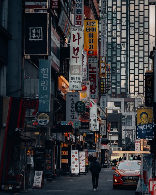 Free Lively city scene in a modern urban alley filled with neon banners and shops. Stock Photo