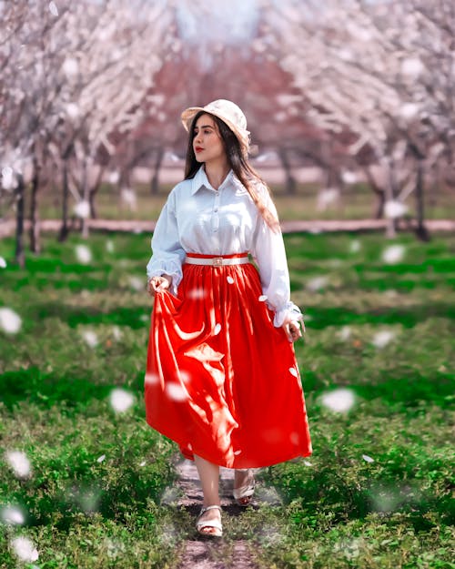 Young Woman in a White Shirt and Red Skirt Posing in a Park 