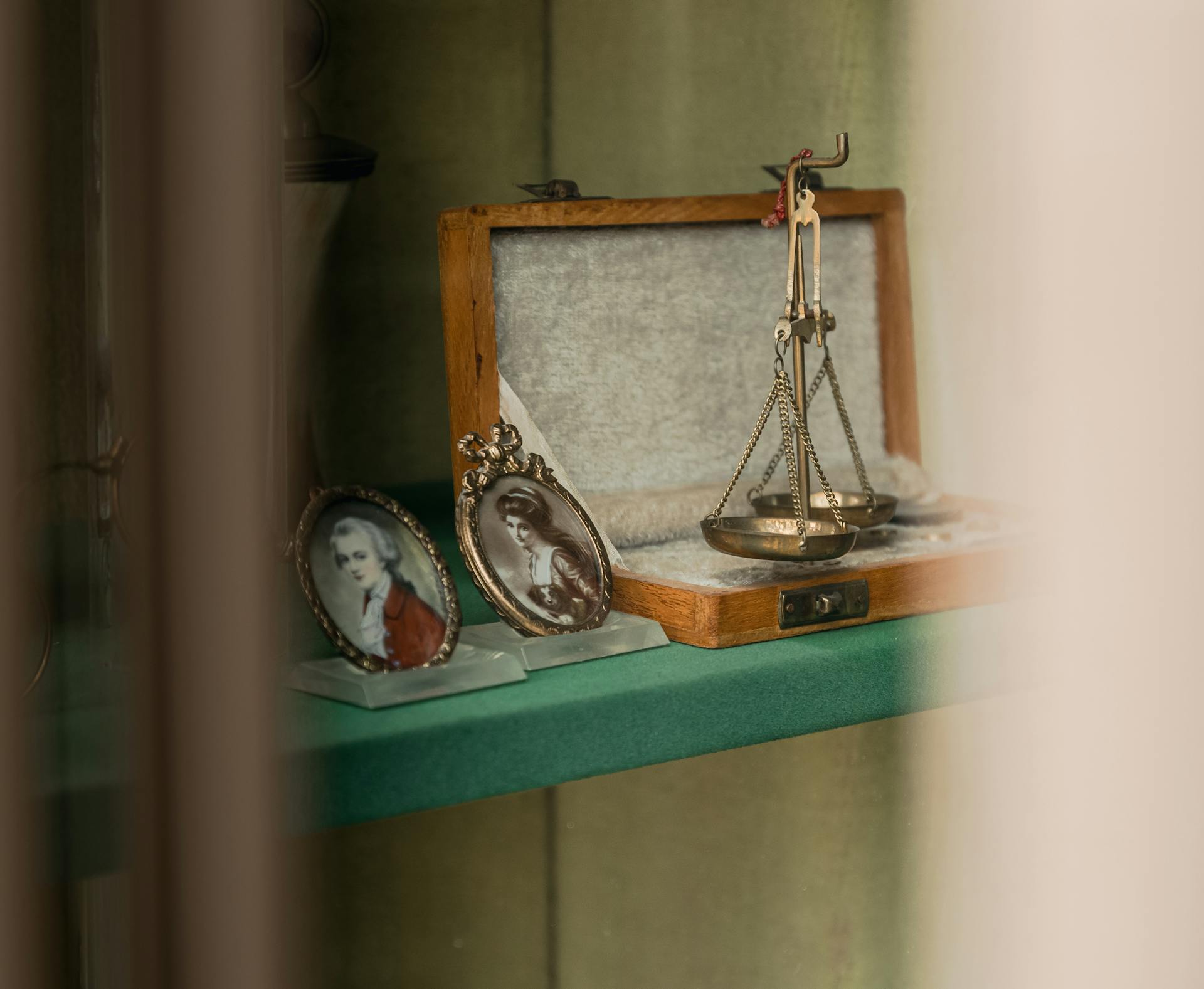 Elegant vintage balance scale with framed portraits on a dresser shelf, featuring selective focus and a nostalgic atmosphere.