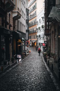 Narrow cobblestone street in İstanbul lined with historic buildings, captured at dusk.