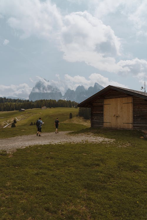 People Walking near Barn in Mountains