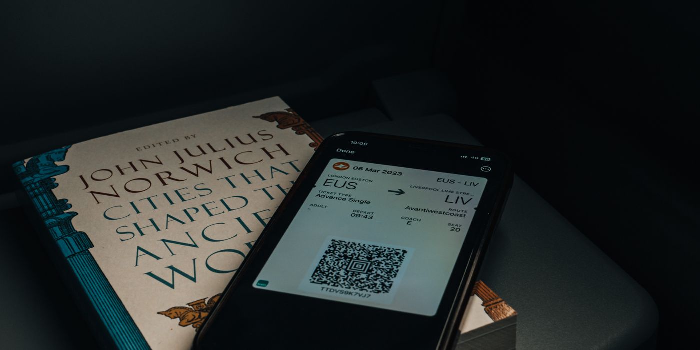 Traveler holding a smartphone showing a travel booking app screen