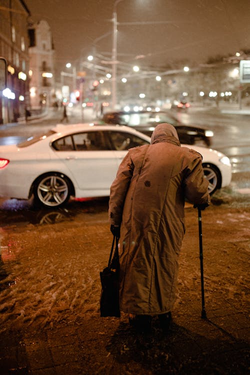 An Elderly Woman with a Walking Stick at the Pedestrian Crossing