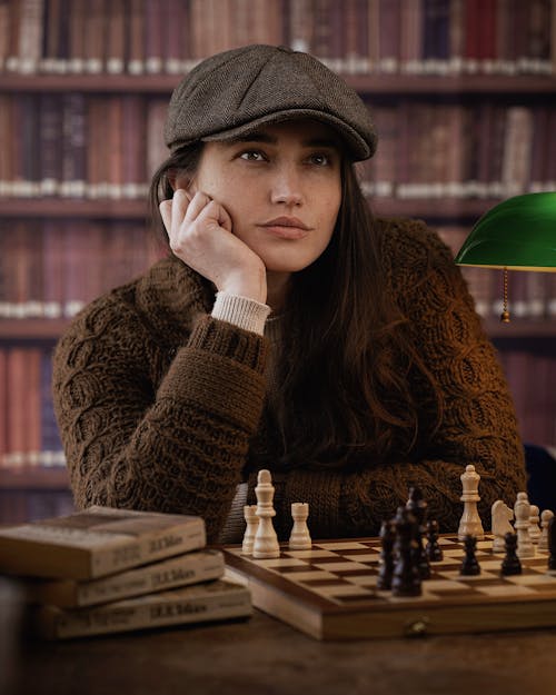 Pensive Woman Sitting at a Chessboard with Her Head Resting on Her Hand