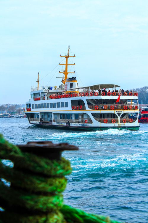 Free Large ferry sails near the coast with clear skies, vivid waters, and distant shoreline. Stock Photo