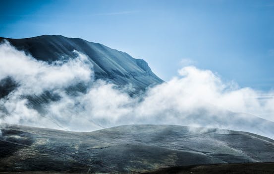A breathtaking view of misty mountains under a clear blue sky, creating a serene landscape.