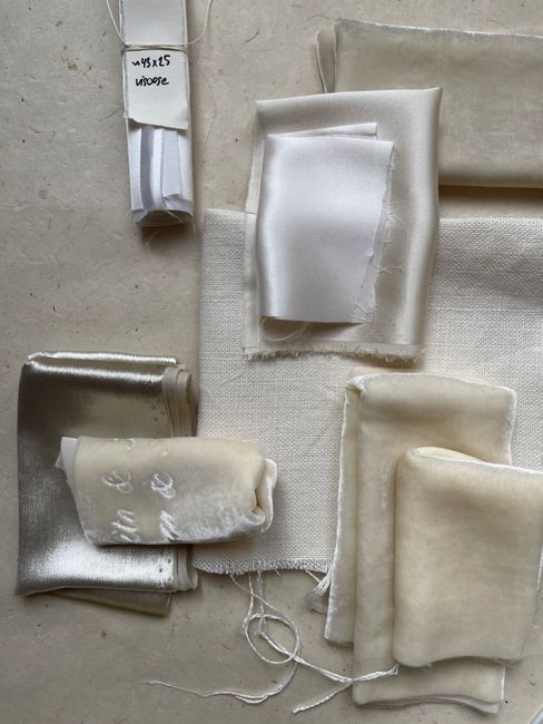 A collection of fabric swatches in neutral tones displayed on a beige surface.