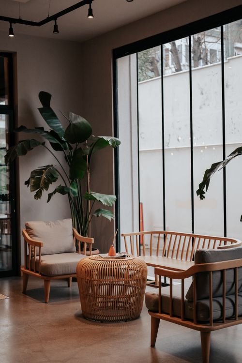 Free A serene indoor seating area with plants, wooden furniture, and large windows. Stock Photo