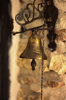 Close-up of a retro brass doorbell mounted on a rustic stone wall, showcasing intricate metalwork.