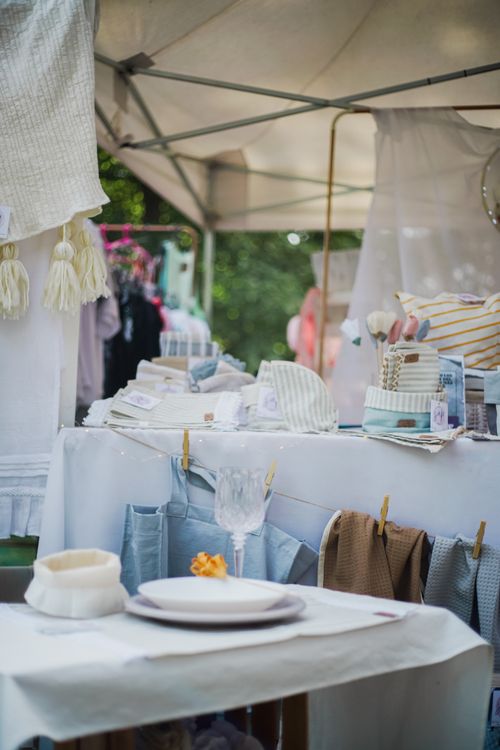 Free A charming market stall displaying textiles and tableware under a canopy at a vibrant outdoor market. Stock Photo
