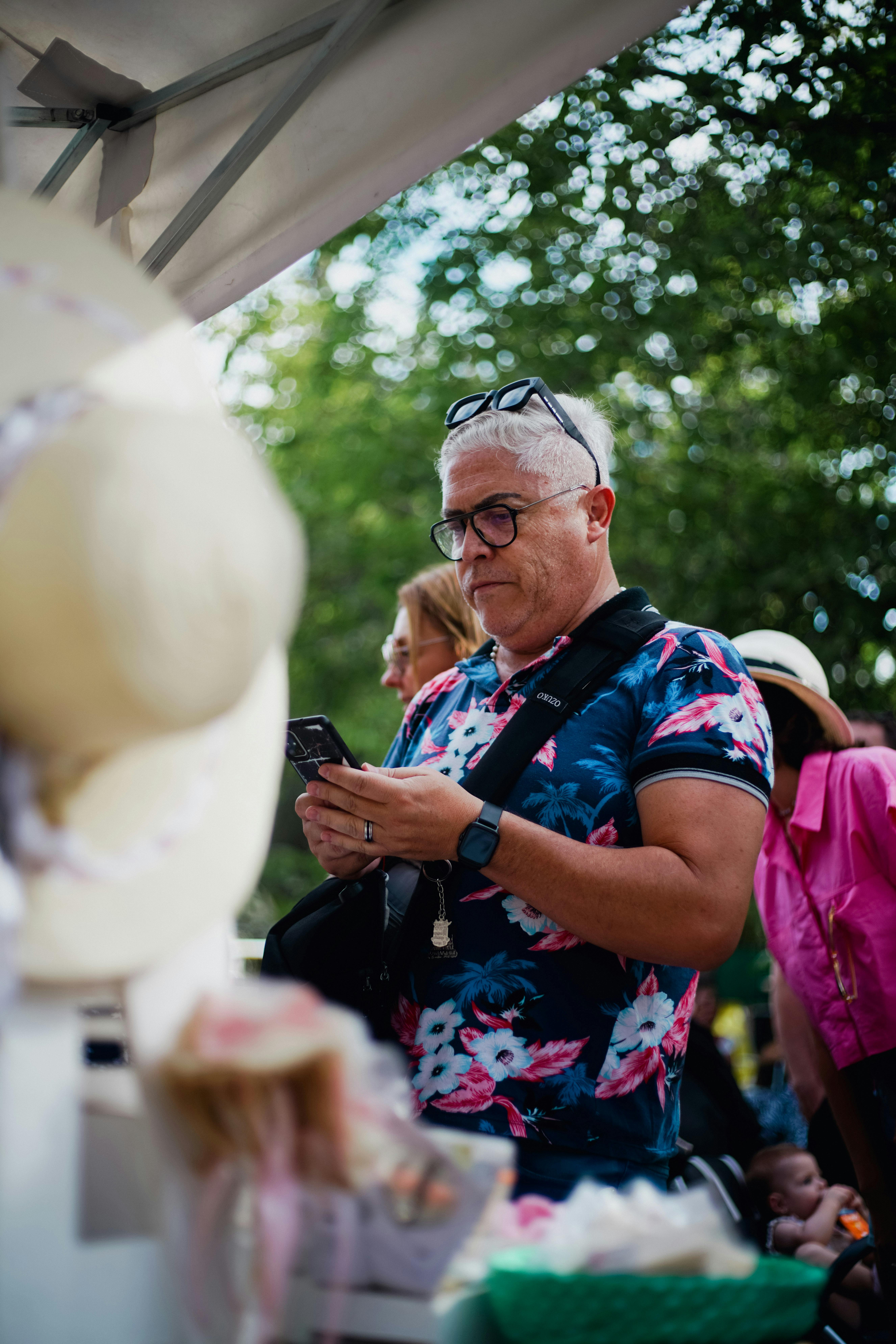 Adult man browsing merchandise at an outdoor market. Vibrant atmosphere captured during daytime shopping.