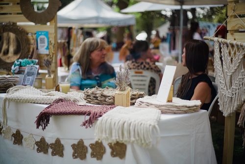 Free A vibrant street market scene displaying handmade woolen crafts with two women interacting. Stock Photo