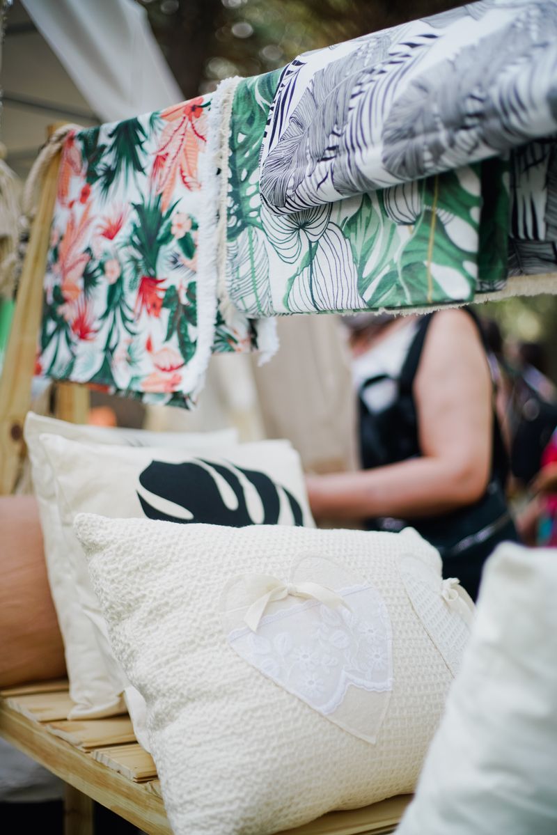 Vibrant display of patterned textiles and pillows at an outdoor market stall.