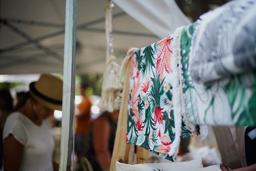 Free Vibrant and diverse textiles on display at an outdoor market with blurred shoppers. Stock Photo