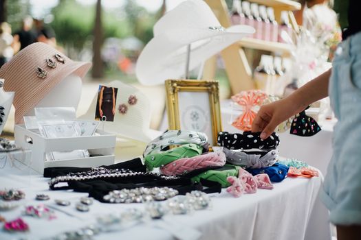 Colorful display of fashion accessories at outdoor market stall featuring hats and headbands.