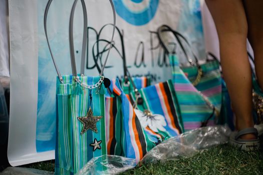 Vibrant striped bags with star charms displayed at an outdoor market.