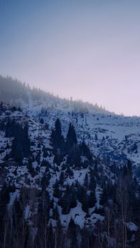 Snow-covered mountains at dusk in Almaty, Kazakhstan, creating a serene winter scene.