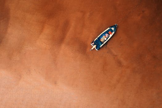 A drone captures a boat on the sandy shore of Chukai, Terengganu, Malaysia, offering a breathtaking aerial perspective.