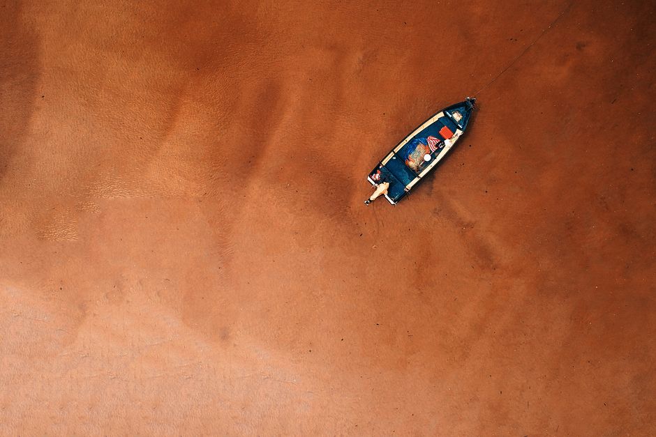 A drone captures a boat on the sandy shore of Chukai, Terengganu, Malaysia, offering a breathtaking aerial perspective.