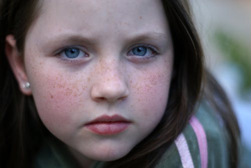 A close up of a young girl with freckles