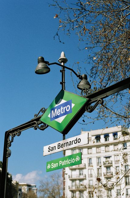 A metro sign in Madrid with a clear blue sky, capturing urban city life.