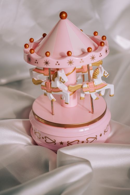 Free Delicate pink carousel music box with white horses on satin backdrop. Ideal for gifts. Stock Photo
