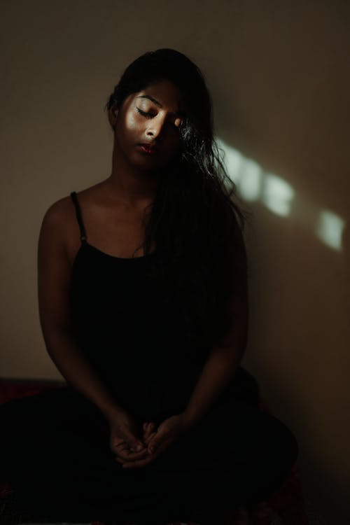 Brunette Meditating in Dark Room