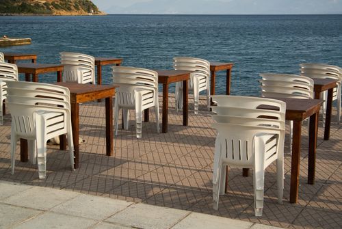 Free Empty seaside restaurant with chairs and tables overlooking the ocean, suggesting a tranquil, offseason setting. Stock Photo