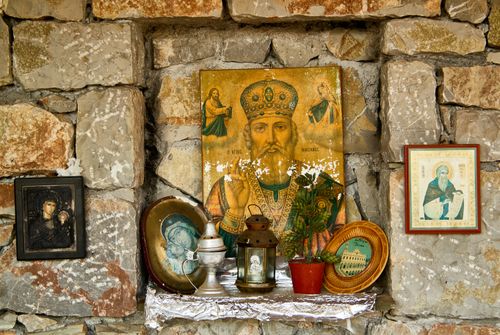 Free A close-up of an ornate religious display with icons and plants on a stone wall. Stock Photo