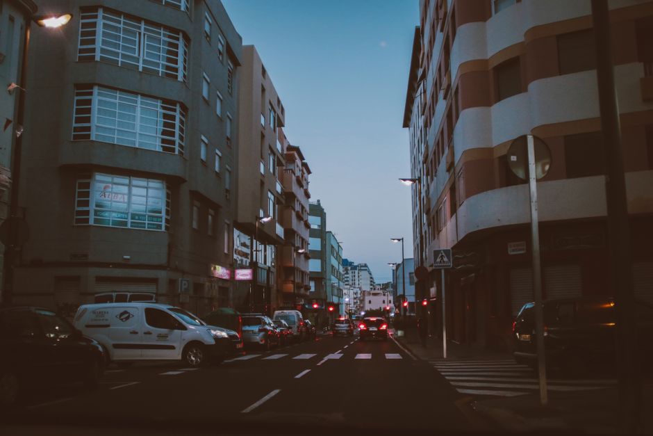 El tráfico fluye en una calle urbana concurrida en Tenerife al anochecer, mostrando la vida de la ciudad.