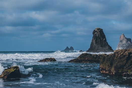 Stunning coastal rock formations with waves crashing under a moody sky.