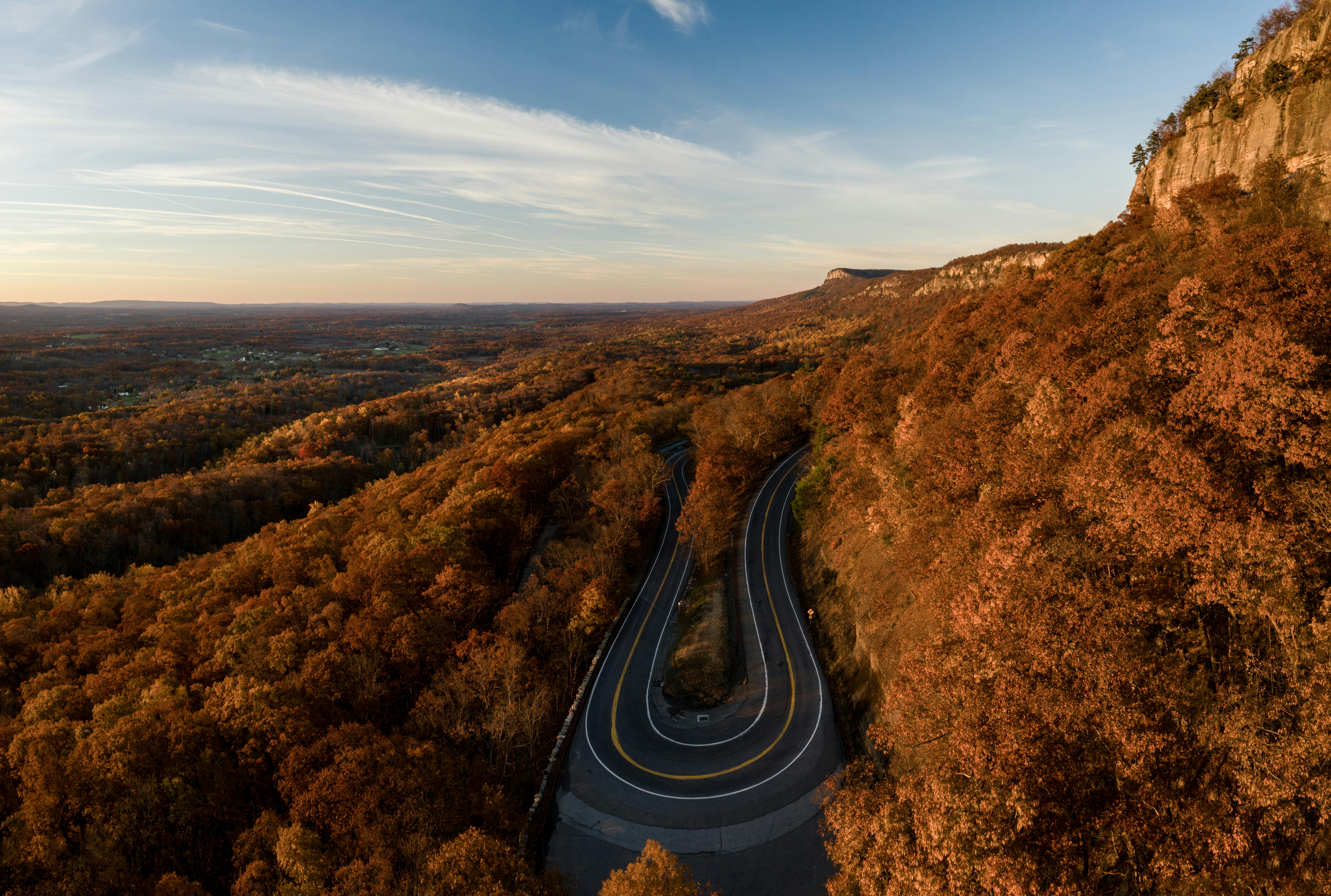 从空中俯瞰，蜿蜒的道路穿过充满活力的秋日森林与山脉，景色壮丽