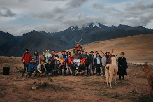 A diverse group poses with alpacas against the majestic Andes Mountains, Peru.