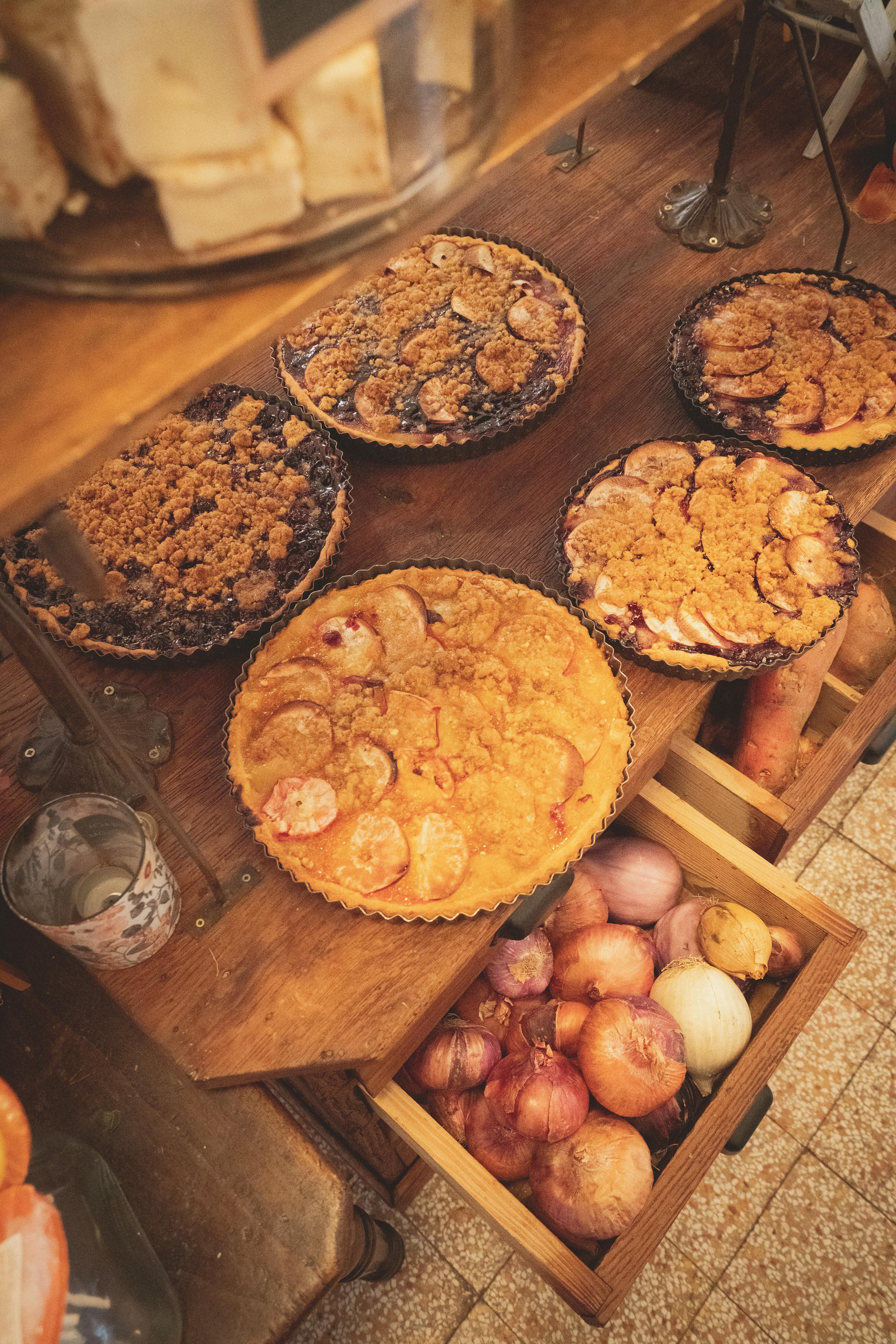 Free Assorted fruit tarts displayed in a cozy kitchen setting with onions below. Stock Photo