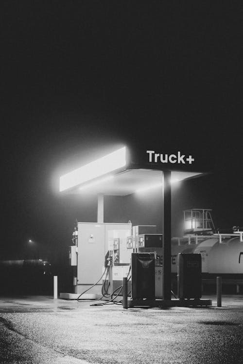 Black and White Photo of an Illuminated Gas Station at Night