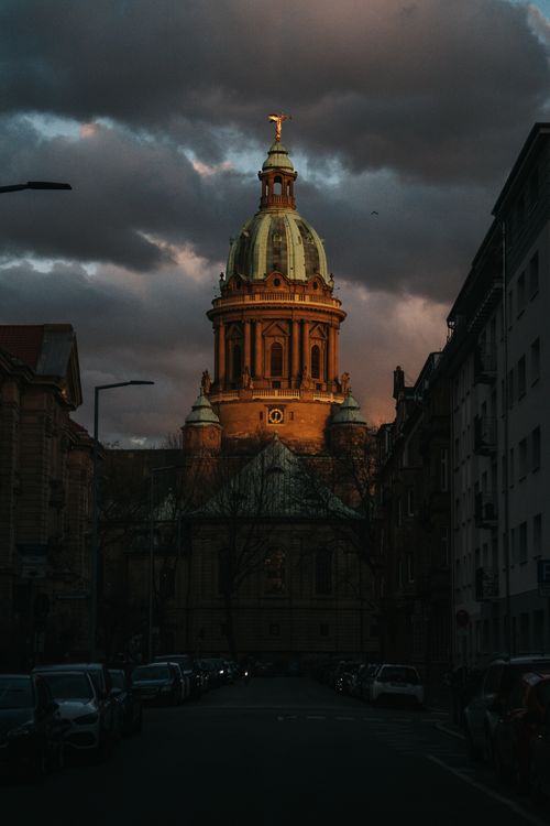 Free Stunning view of a historic cathedral dome illuminated by sunset, creating a dramatic urban scene. Stock Photo
