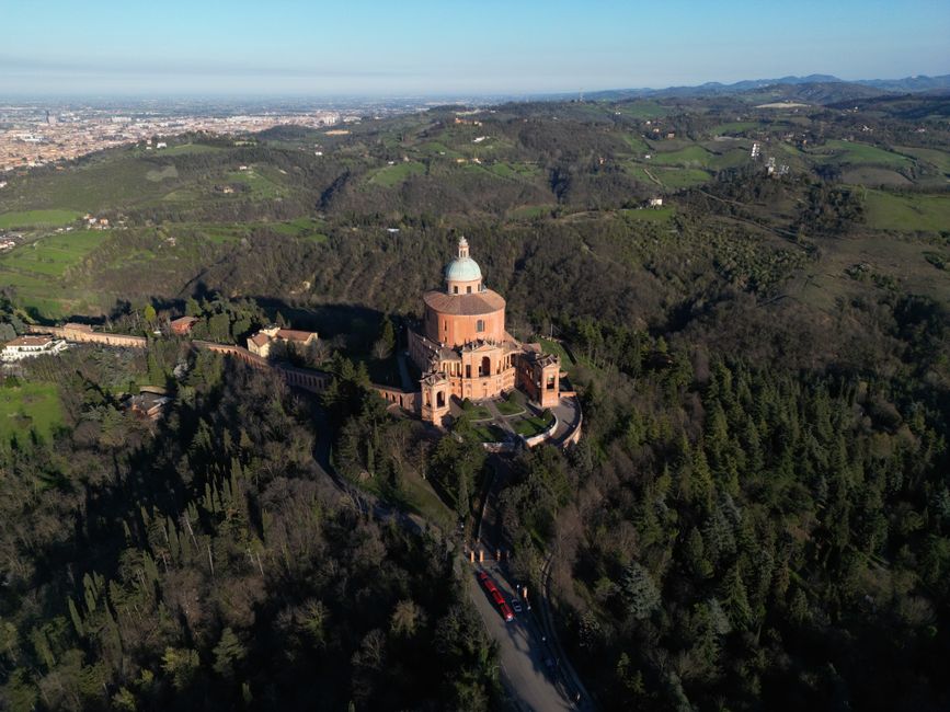 Aerial photograph of the Sanctuary of the Madonna di San Luca in Bologna, surrounded by lush Italian landscapes.