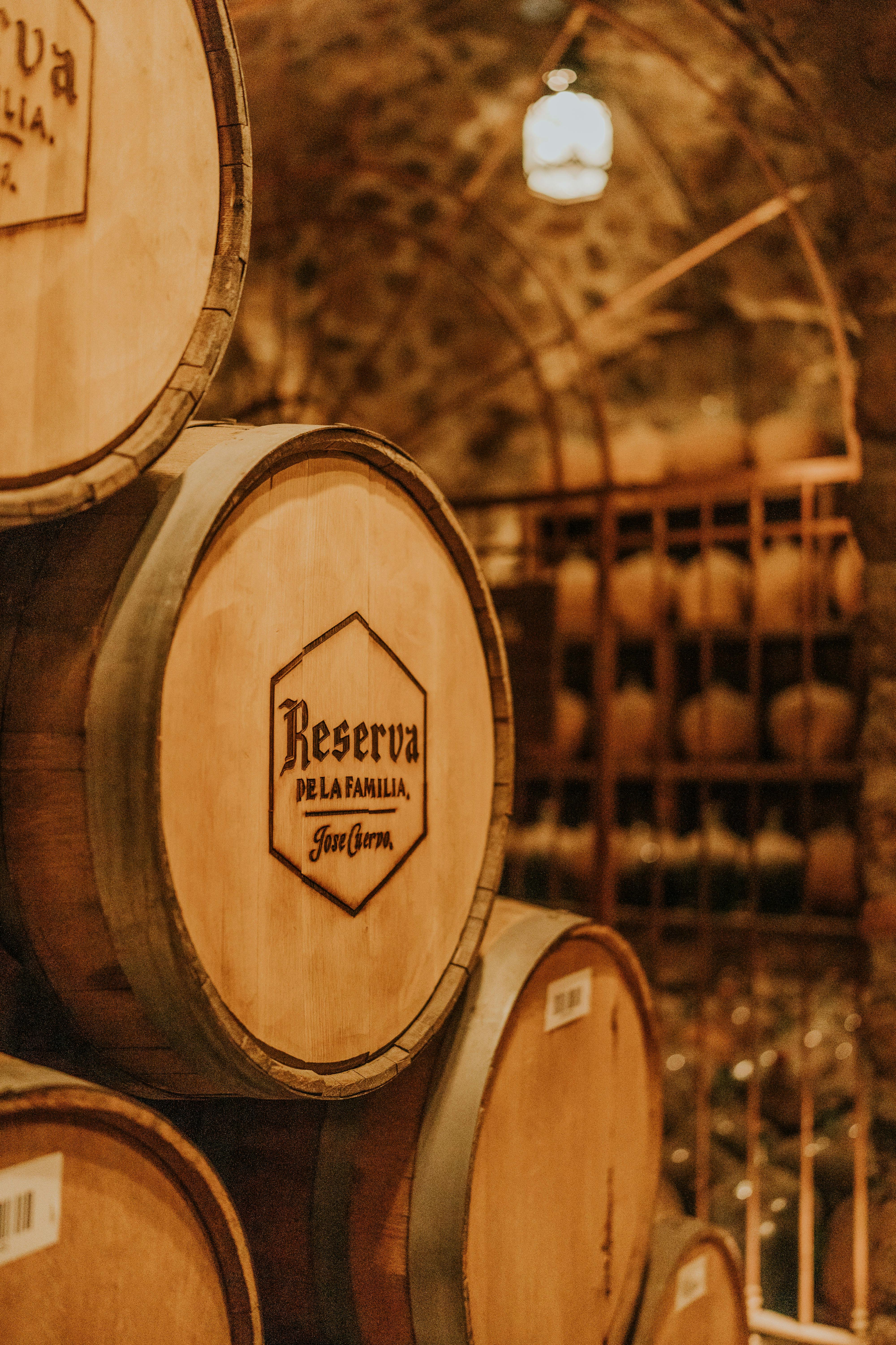 Wooden wine barrels stacked in a warm, rustic cellar setting, emphasizing tradition and craftsmanship.