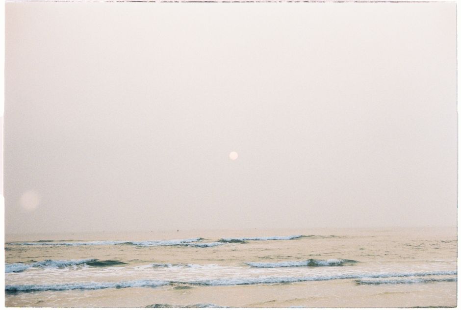 Peaceful seascape with soft waves under an overcast sky, evoking tranquility.