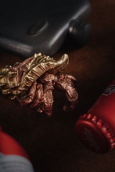 Intricate sculpture of a golden snake and crab surrounded by red bottles, focusing on detail.